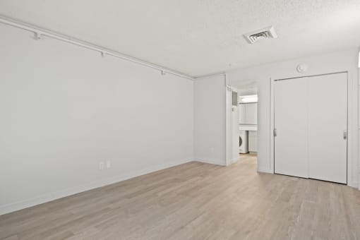 an empty living room with white walls and wood flooring at AVIA Lofts on Liberty Ridge, Florida, 32256