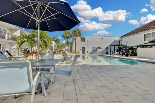 a swimming pool with tables and chairs next to a building