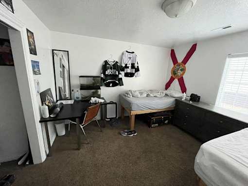 A room with a bed, desk, and a ceiling fan.