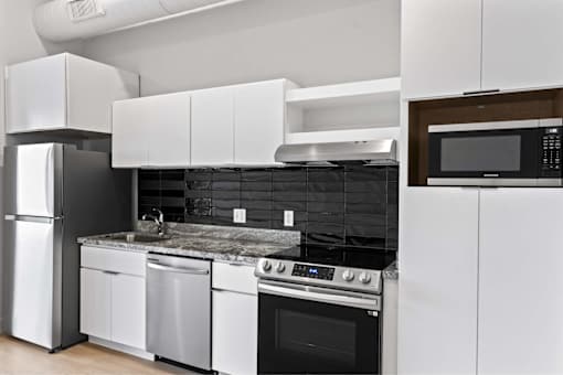 A modern kitchen with white cabinets and black appliances.