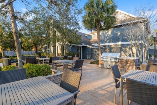 a patio with tables and chairs and a grill at AVIA Lofts on Liberty Ridge, Jacksonville, FL, 32256
