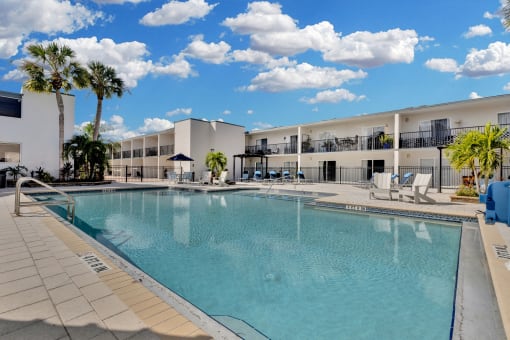 a large swimming pool in front of a hotel with palm trees