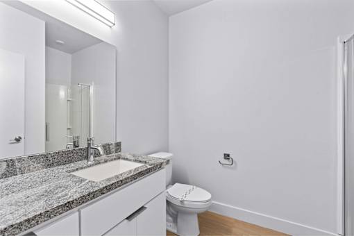A bathroom with a toilet, sink, and mirror.