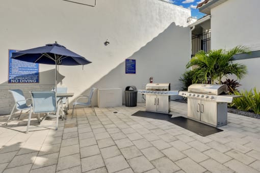 a patio with a grill and a table with chairs and an umbrella