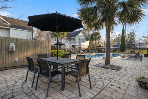 a patio with a table and chairs under an umbrella next to a pool at AVIA Lofts on Liberty Ridge, Florida