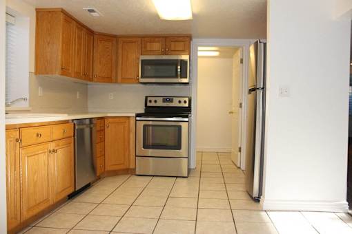 A kitchen with wooden cabinets and a stainless steel oven.