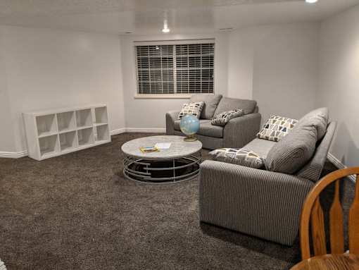 A living room with a grey couch, a white coffee table, and a grey rug.