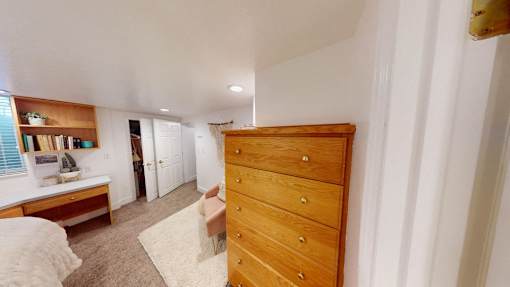 A long wooden chest of drawers is in a room with white walls.