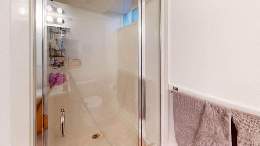 A bathroom with a glass shower door and a towel hanging on the wall.