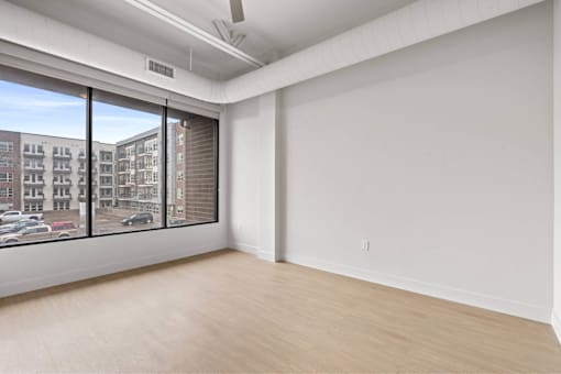 Empty room with a window overlooking a parking lot.