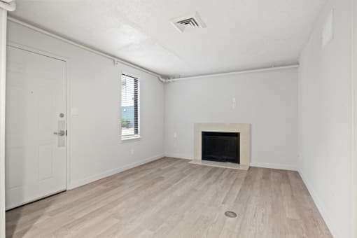 an empty living room with a fireplace and wooden floors at AVIA Lofts on Liberty Ridge, Jacksonville, FL, 32256