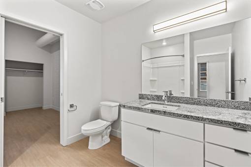 A bathroom with a toilet, sink, and mirror.