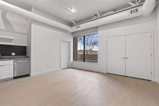 A large empty room with white walls and wooden flooring.