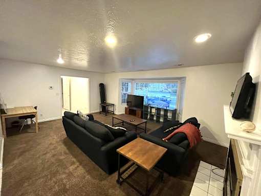 A living room with a black couch and a television on the wall.