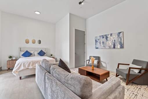 A modern bedroom with a large bed and a grey couch.