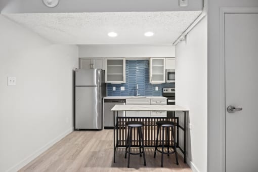 a kitchen with a island and stools and a stainless steel refrigerator at AVIA Lofts on Liberty Ridge, Florida, 32256