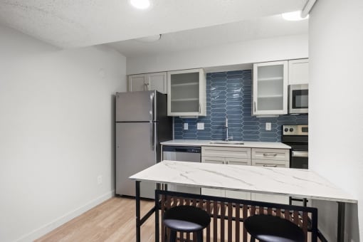 a kitchen with a white island and a stainless steel refrigerator at AVIA Lofts on Liberty Ridge, Florida, 32256