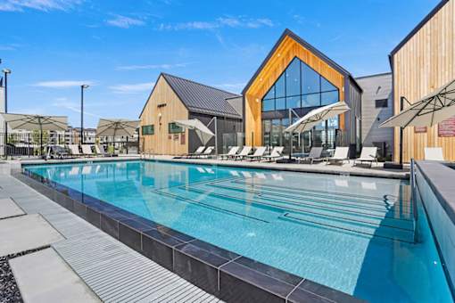 A large swimming pool with a wooden building in the background.