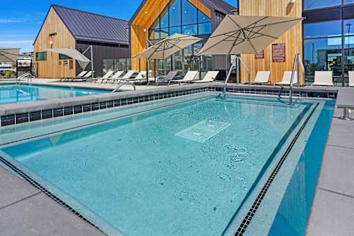 A large swimming pool with a wooden building in the background.