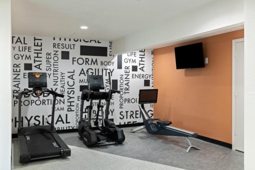 a room with some exercise equipment and a tv on the wall