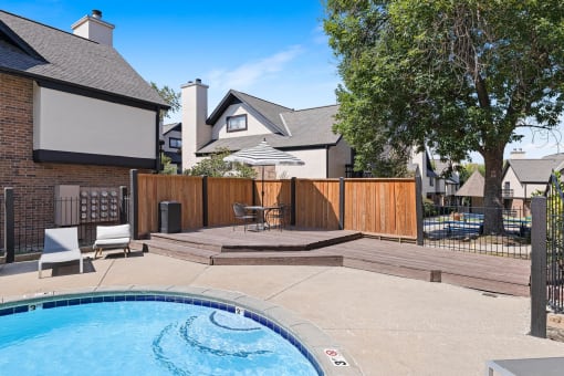 a backyard with a pool and a privacy fence with a house in the background