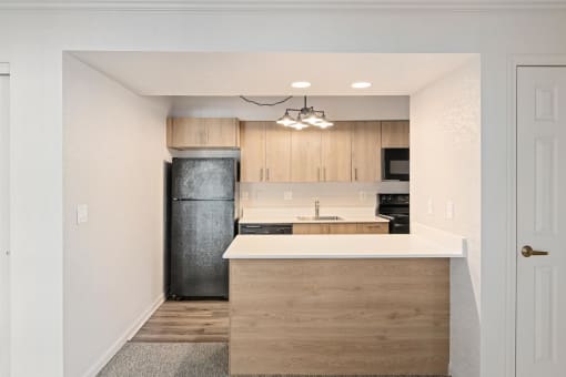 a renovated kitchen with wood cabinets and a black refrigerator