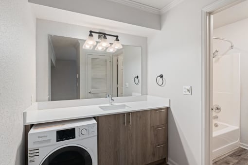 a white laundry room with a sink and a washing machine