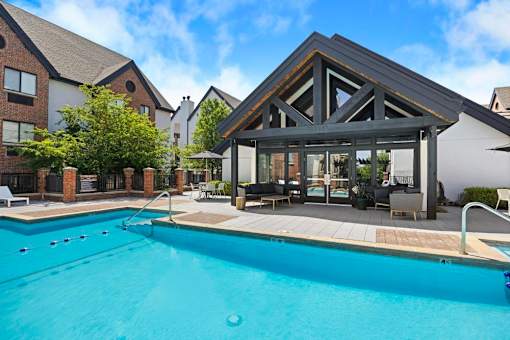 A swimming pool in front of a building with a glass pavilion.