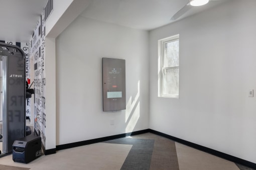 a white room with a window on the left and a black door on the right