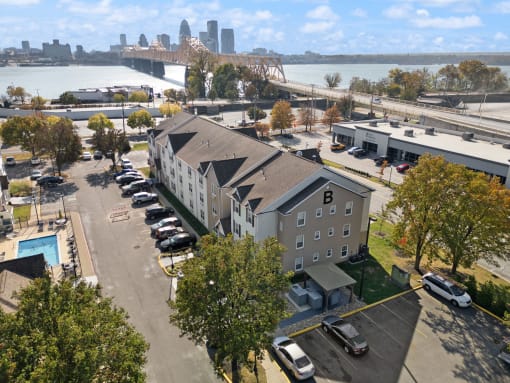 an aerial view of a building with a river and a city in the background