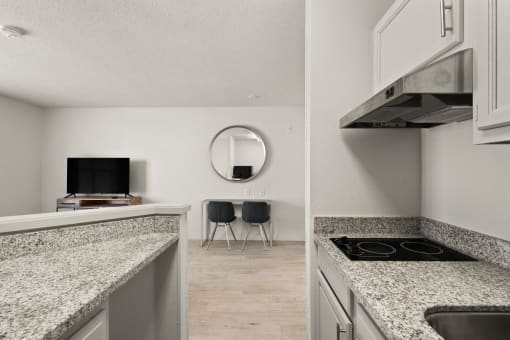 a kitchen with granite counter tops and a living room with a tv