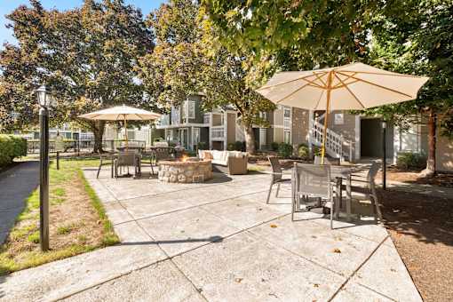A sunny day at the park with a picnic table and chairs under an umbrella.