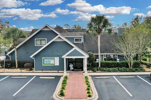 a blue house with a parking lot and palm trees at AVIA Lofts on Liberty Ridge, Florida