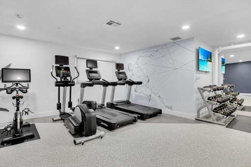 the gym with treadmills and weights and a map on the wall at AVIA Lofts on Liberty Ridge, Florida