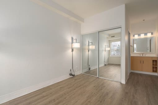 an empty living room with a mirror and a bathroom