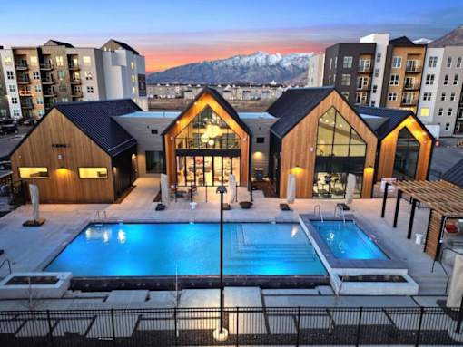 A modern building with a pool in the foreground and snow-capped mountains in the background.