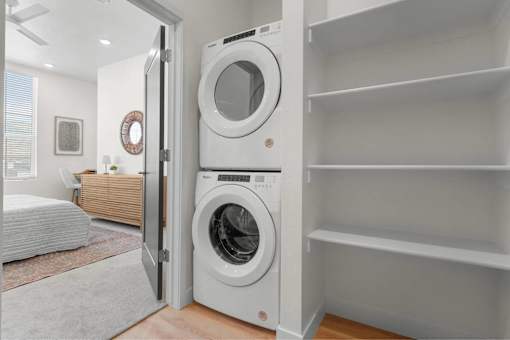 A white washing machine is placed in a white cabinet.