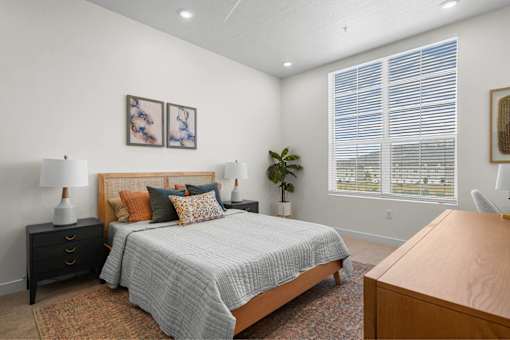 A bedroom with a bed, nightstand, and a painting on the wall.