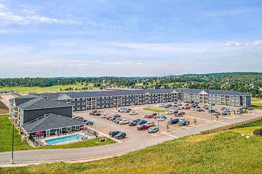 a large building with a pool and parking lot at Red Rock Apartments, Rapid City