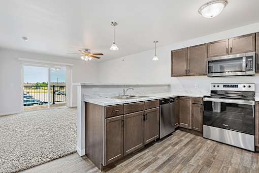 a kitchen with wooden cabinets and stainless steel appliances at Red Rock Apartments, Rapid City