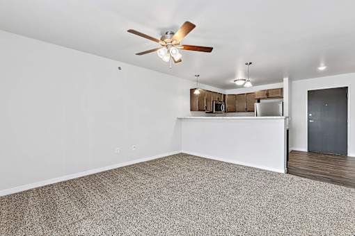 a bedroom with a ceiling fan and a kitchen in the background at Red Rock Apartments, South Dakota