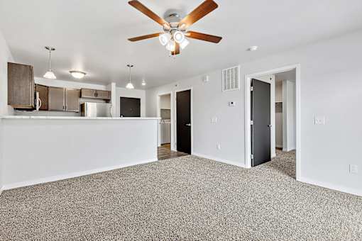 a living room with a ceiling fan and a kitchen in the background at Red Rock Apartments, South Dakota 57702