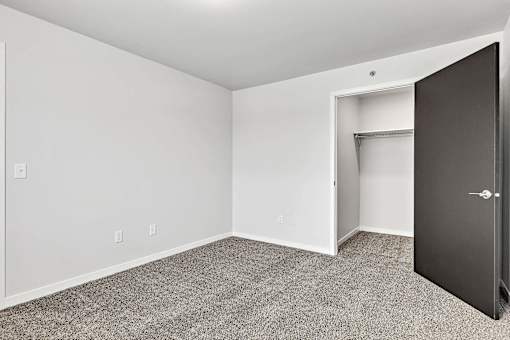 a bedroom with gray carpet and a closet with a black door at Red Rock Apartments, South Dakota 57702