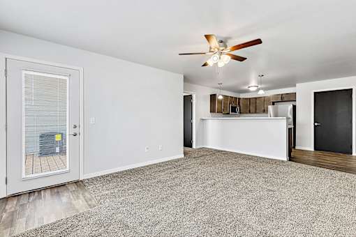 a living room with a ceiling fan and a kitchen in the background at Red Rock Apartments, Rapid City, SD, 57702