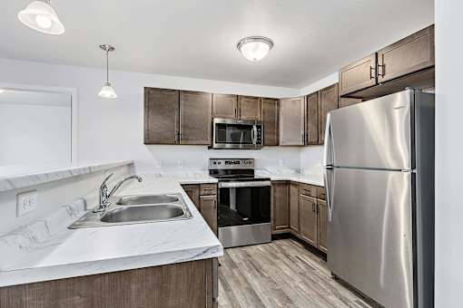 a kitchen with wooden cabinets and stainless steel appliances at Red Rock Apartments, Rapid City