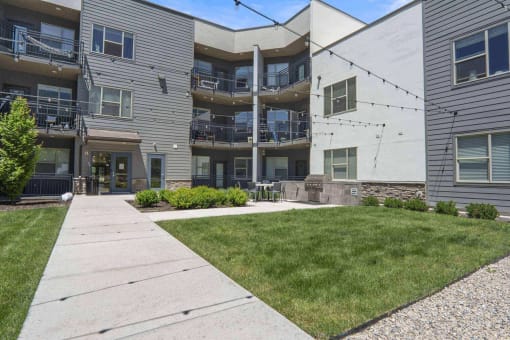 a view of the back of the building with a lawn and patio at The Flats at Riverwoods, Provo, UT