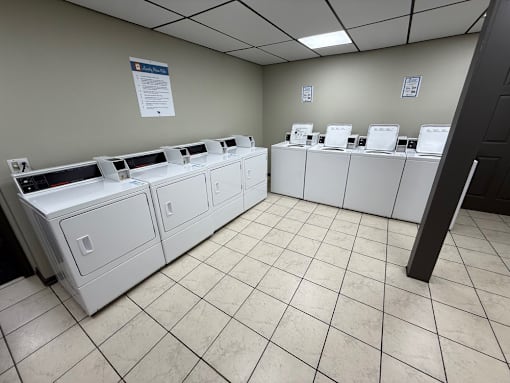 A room with white tiled floors and white cabinets with black tops.