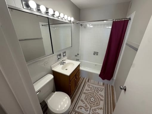 A bathroom with a toilet, sink, and mirror.