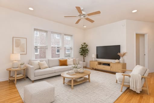 A living room with a white couch, a wooden coffee table, and a ceiling fan.