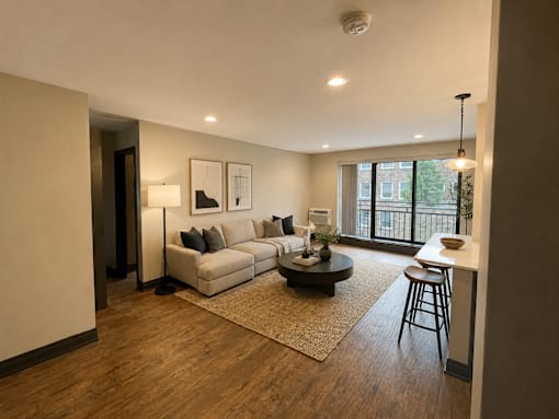 A living room with a white couch, a coffee table, and a window.